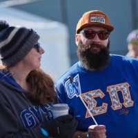 Man with sunglasses looking at camera, woman next to him wear hat looking off to the side